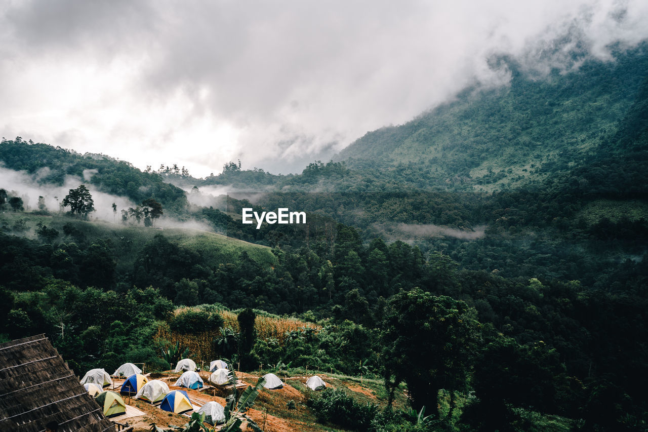 Scenic view of tents on mountains against sky