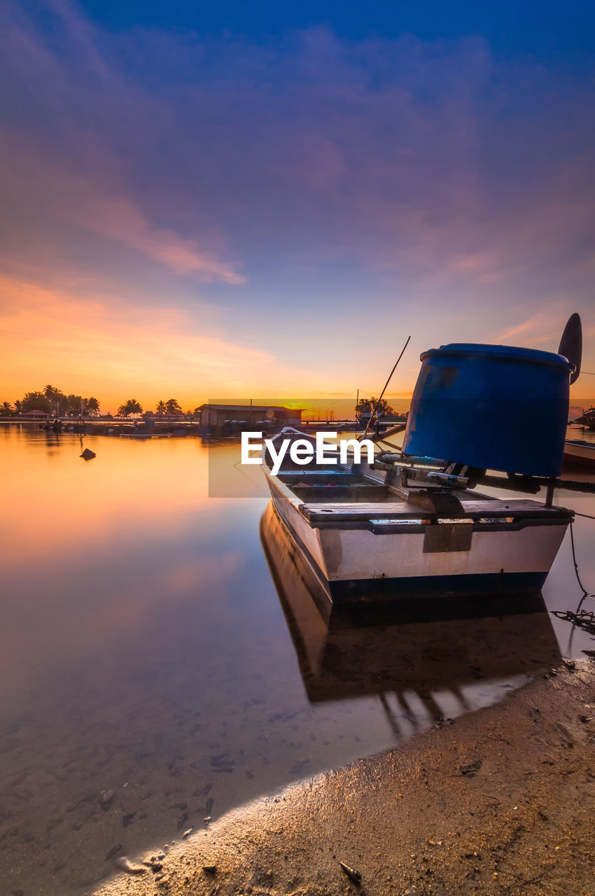 Boat moored on sea against sky during sunset