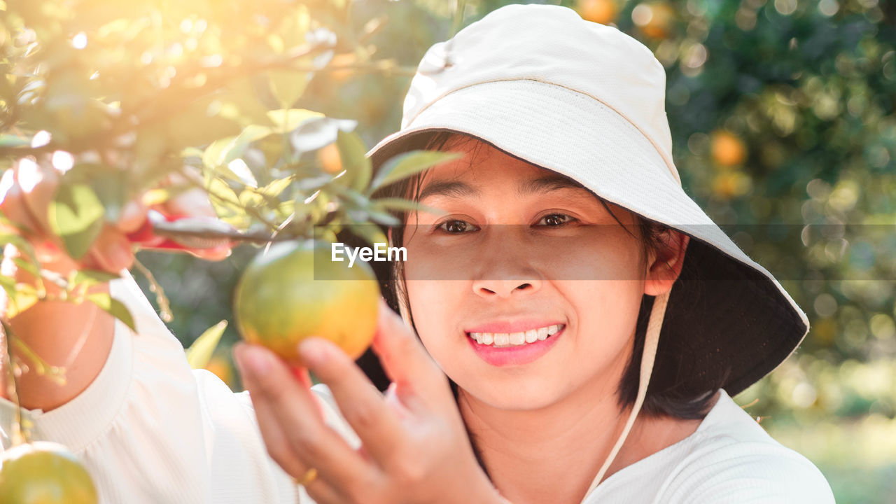 Close-up of smiling woman picking fruit from plants