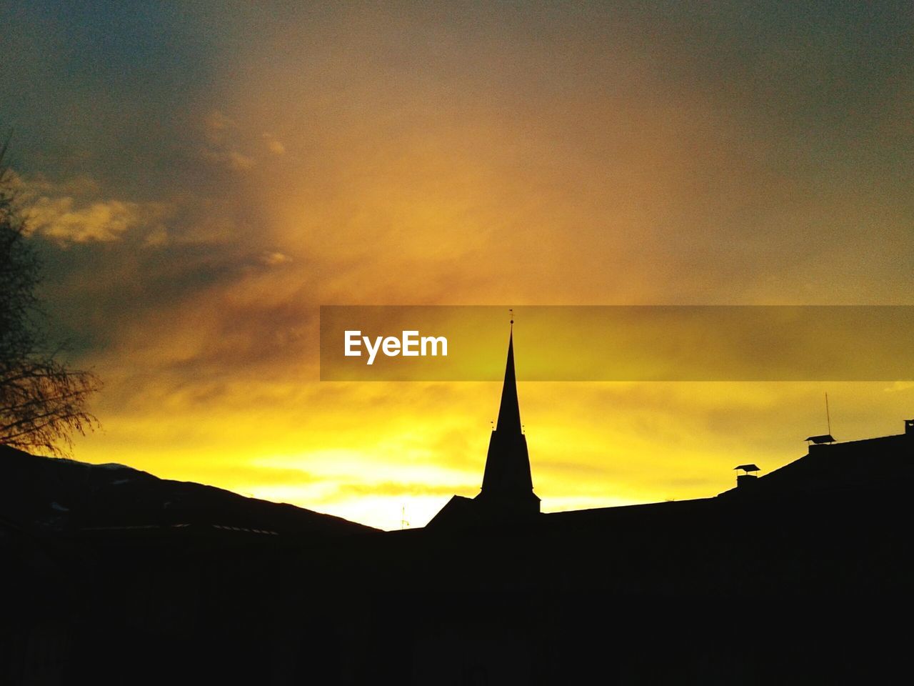 Sharp church pinnacle against moody sunset sky
