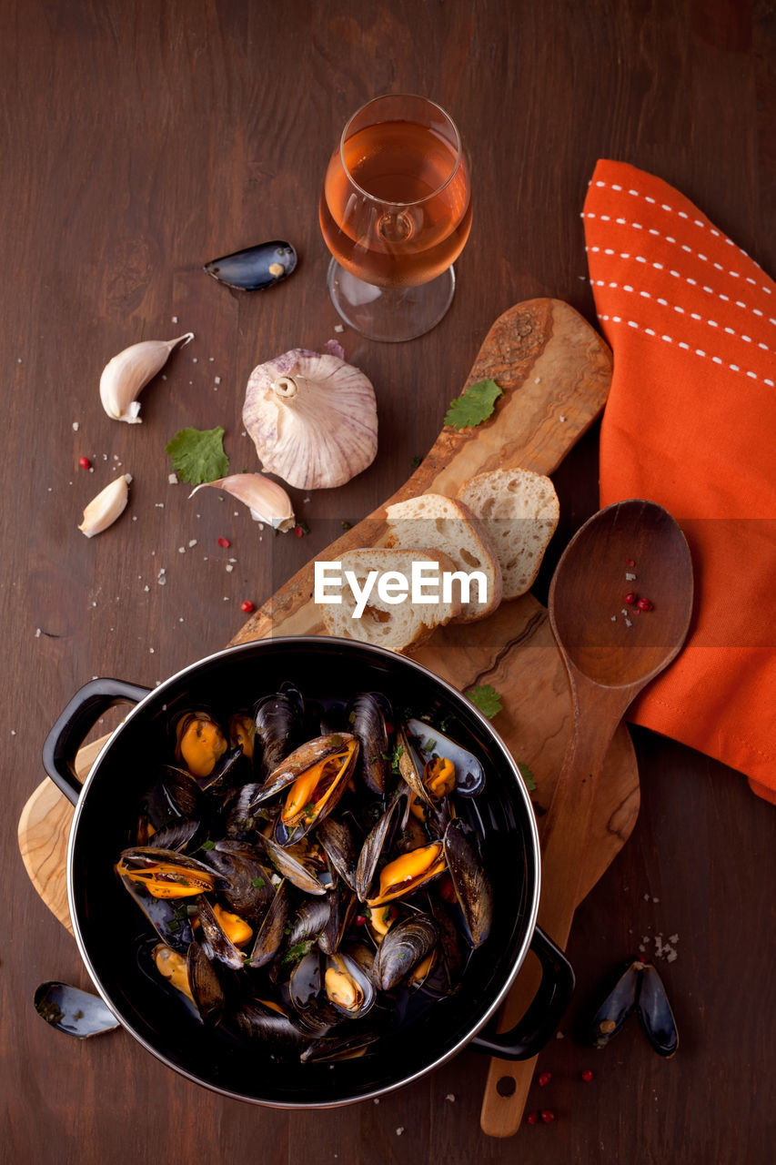 High angle view of mussels with bread and garlic on table