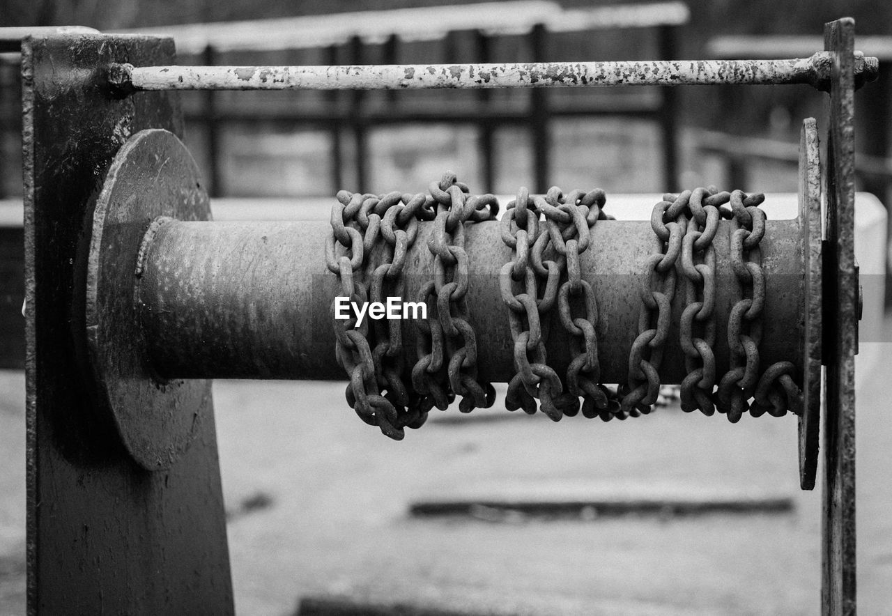 CLOSE-UP OF RUSTY CHAIN HANGING ON METAL SURFACE