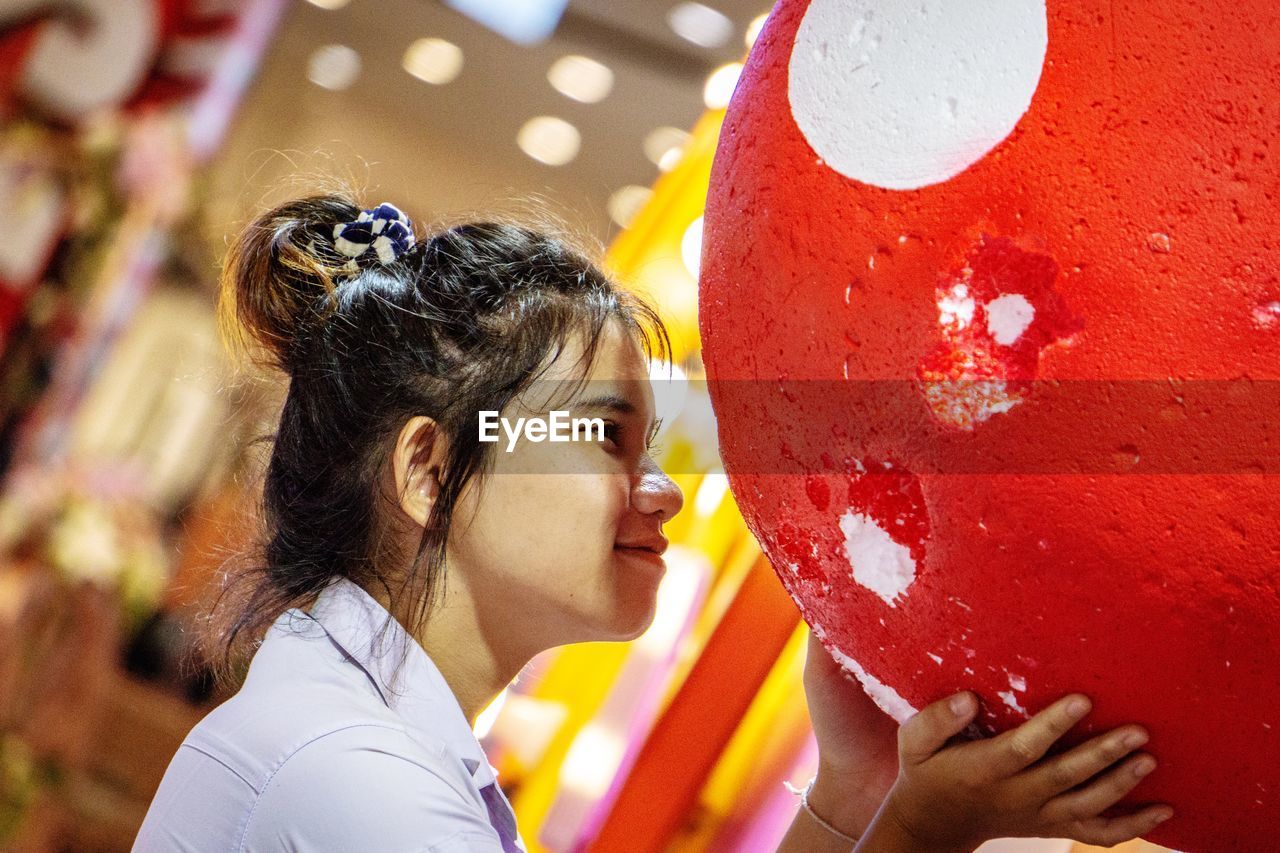 Close-up of smiling young woman holding red ball