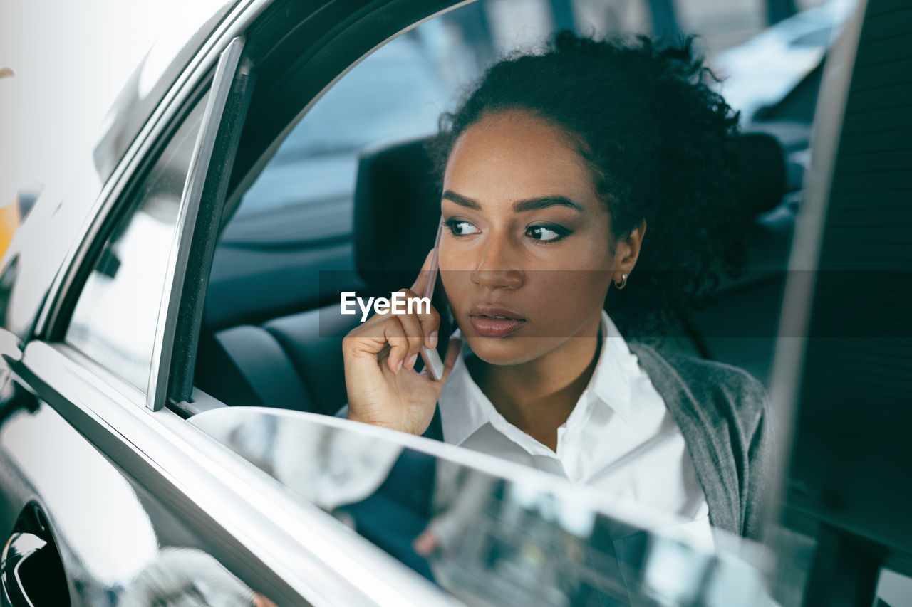 Young woman using smart phone in car