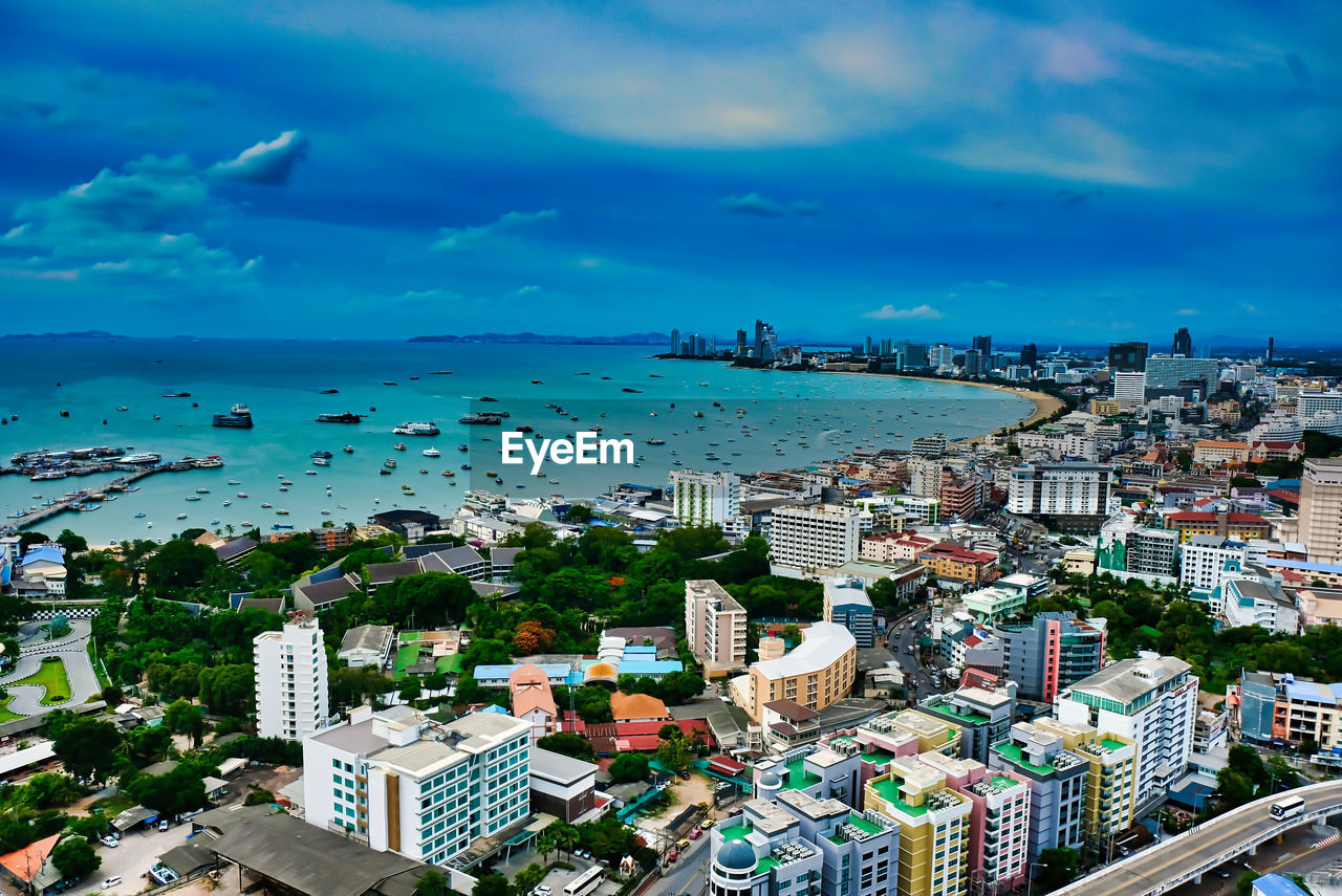 HIGH ANGLE VIEW OF ILLUMINATED CITY BY SEA AGAINST SKY