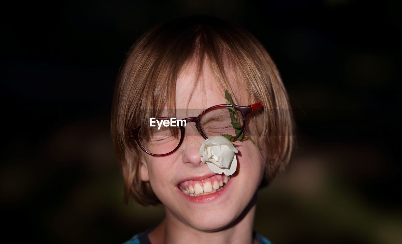 Close-up of smiling boy with flower hitting on face