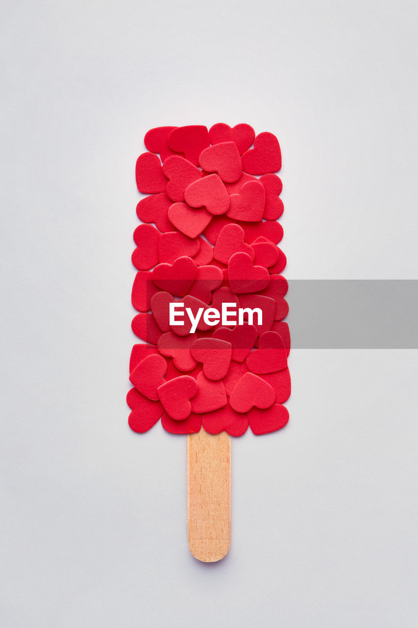 Popsicle made by heart shape sprinkles on white background