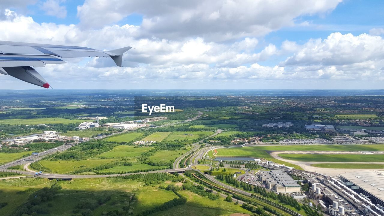 AIRPLANE FLYING OVER LANDSCAPE AGAINST SKY