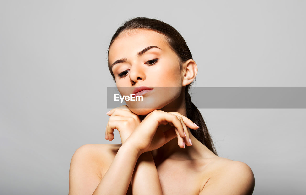 Young woman looking down against gray background