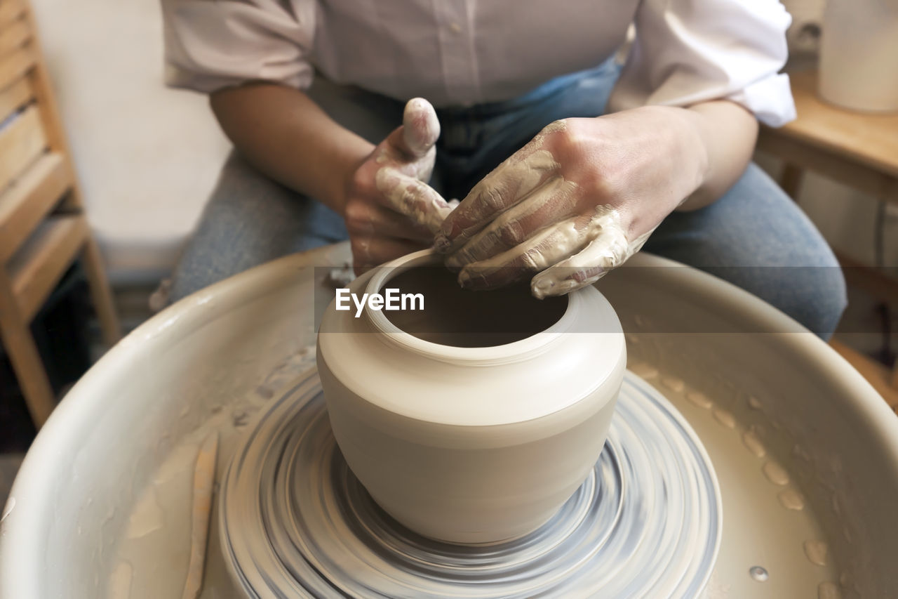 Close-up of potter's hands. an artisan works on a potter's wheel and makes a vase. creating ceramics