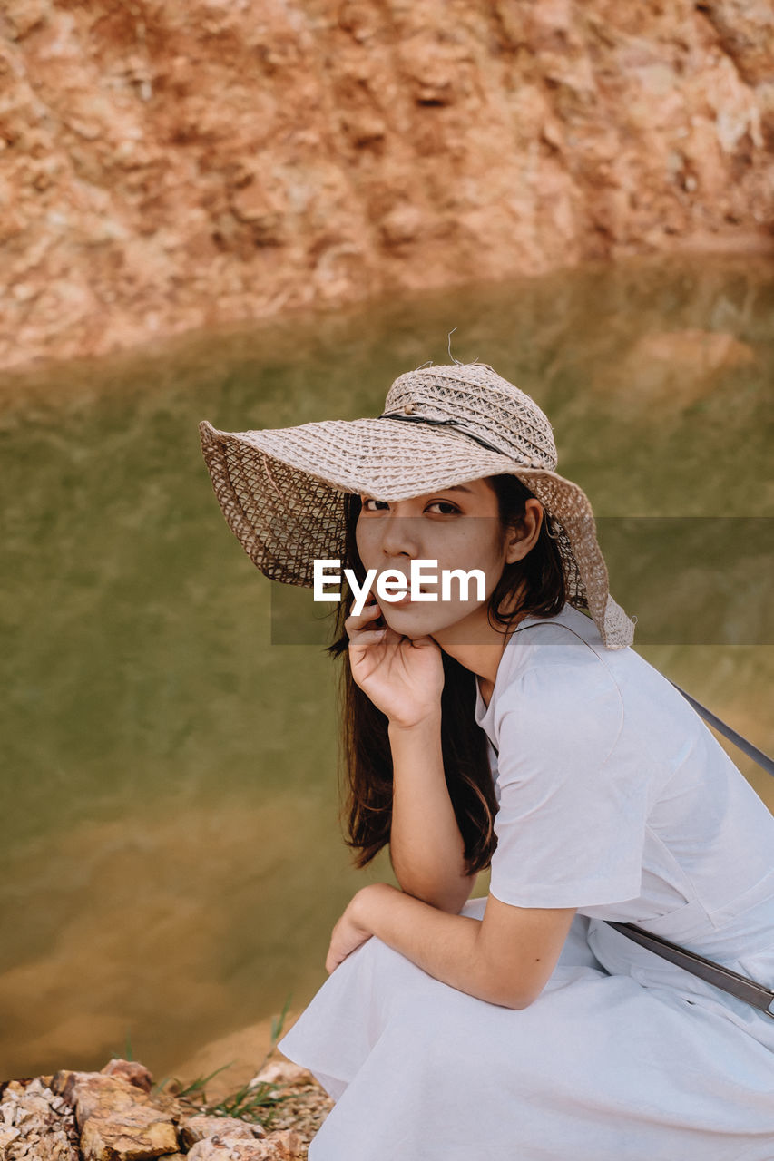 Portrait of young woman sitting by lake