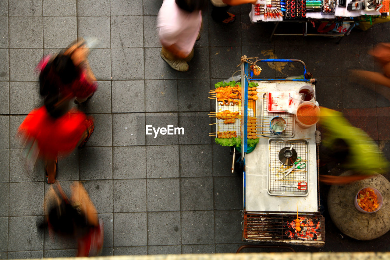 Blurred motion of people by market stall on footpath