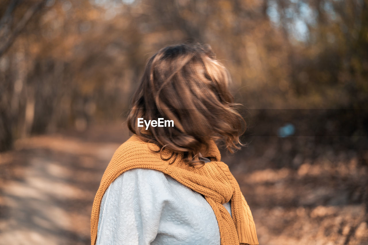 REAR VIEW OF WOMAN STANDING ON ROCK DURING AUTUMN