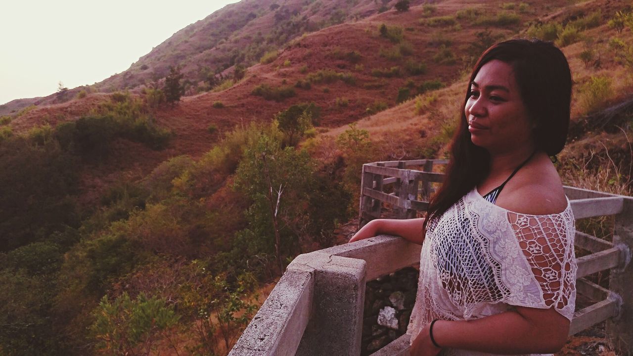 Woman standing by railing on mountain