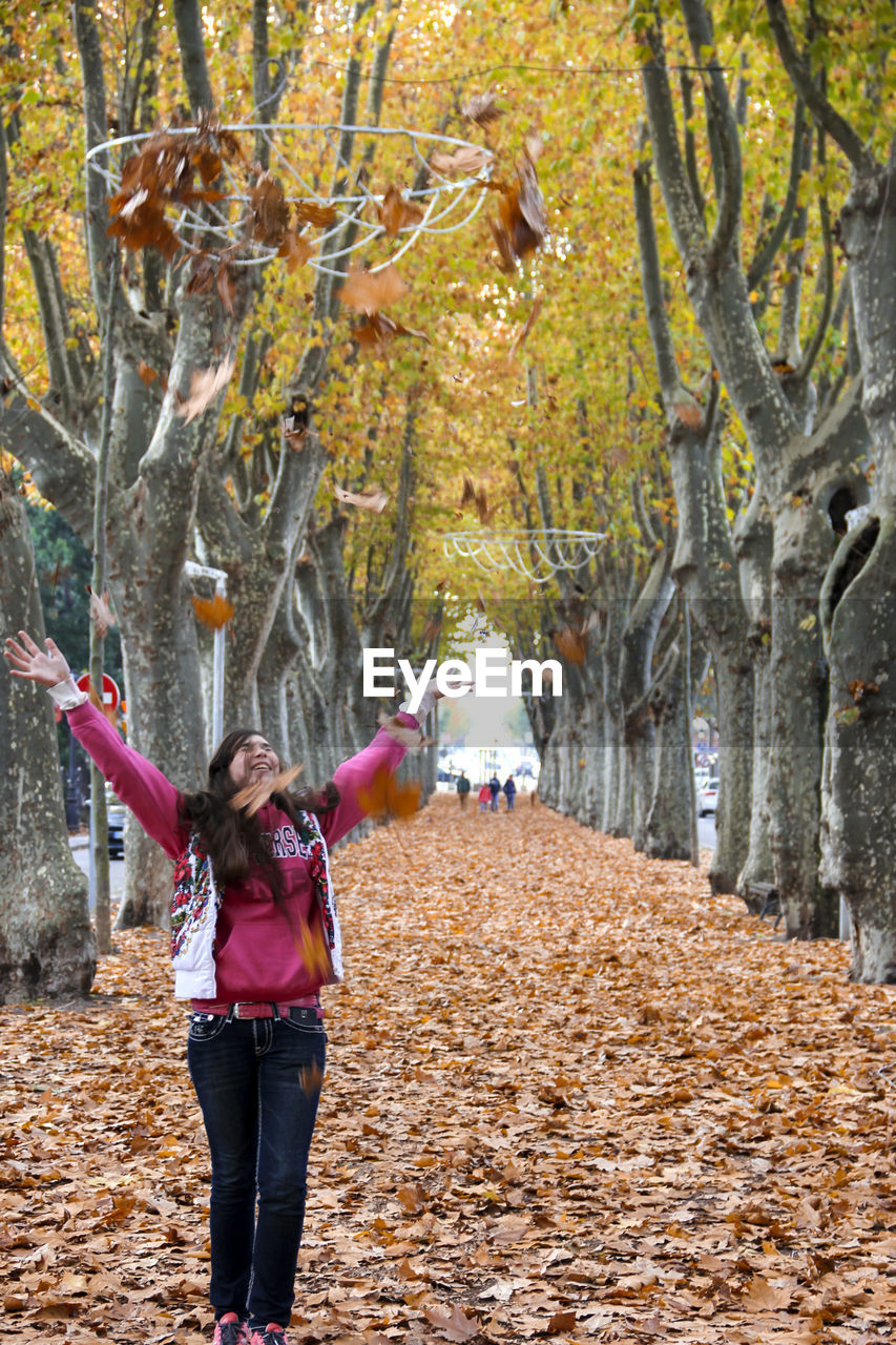 Woman standing by tree in park during autumn