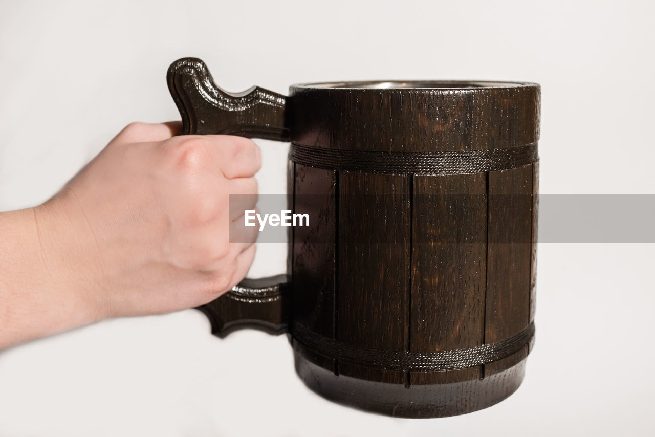 Close-up of hand holding container over white background