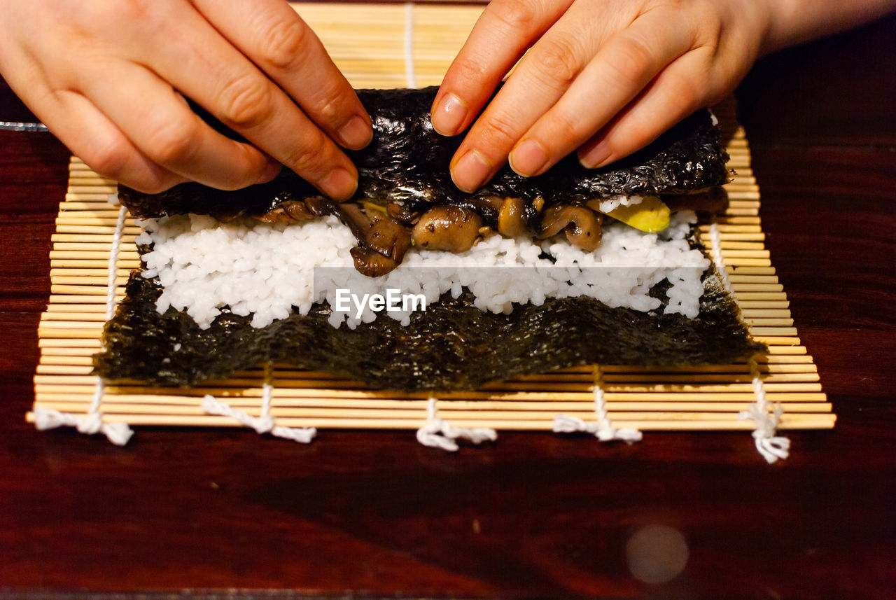 MIDSECTION OF PERSON HOLDING SUSHI ON TRAY