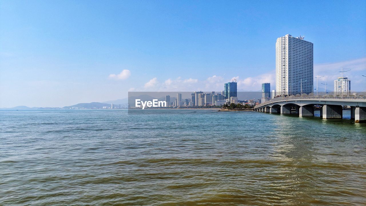 Bridge over sea and buildings against sky