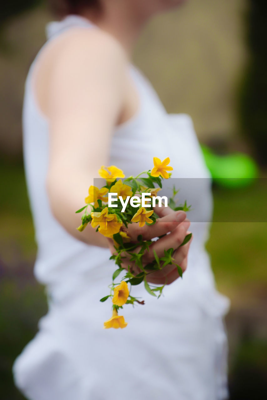 Close-up of woman holding yellow flowering plant