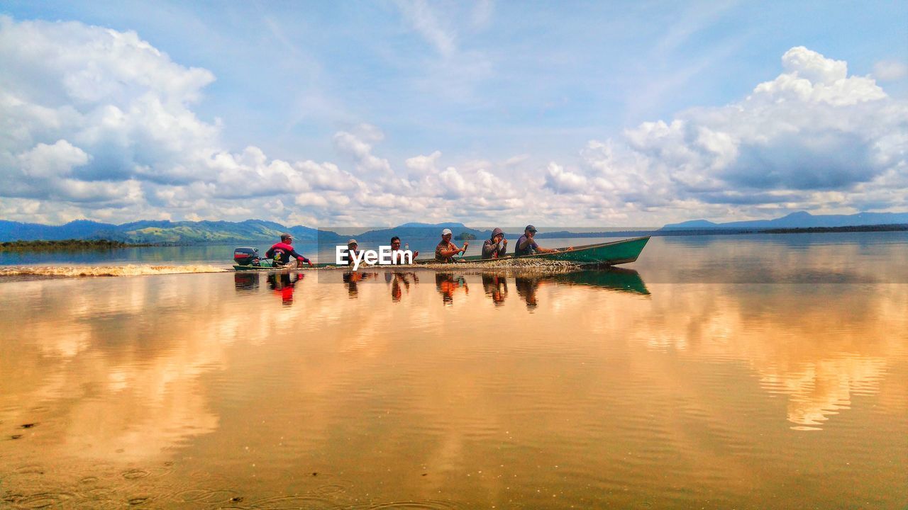 GROUP OF PEOPLE IN BOAT ON LAKE