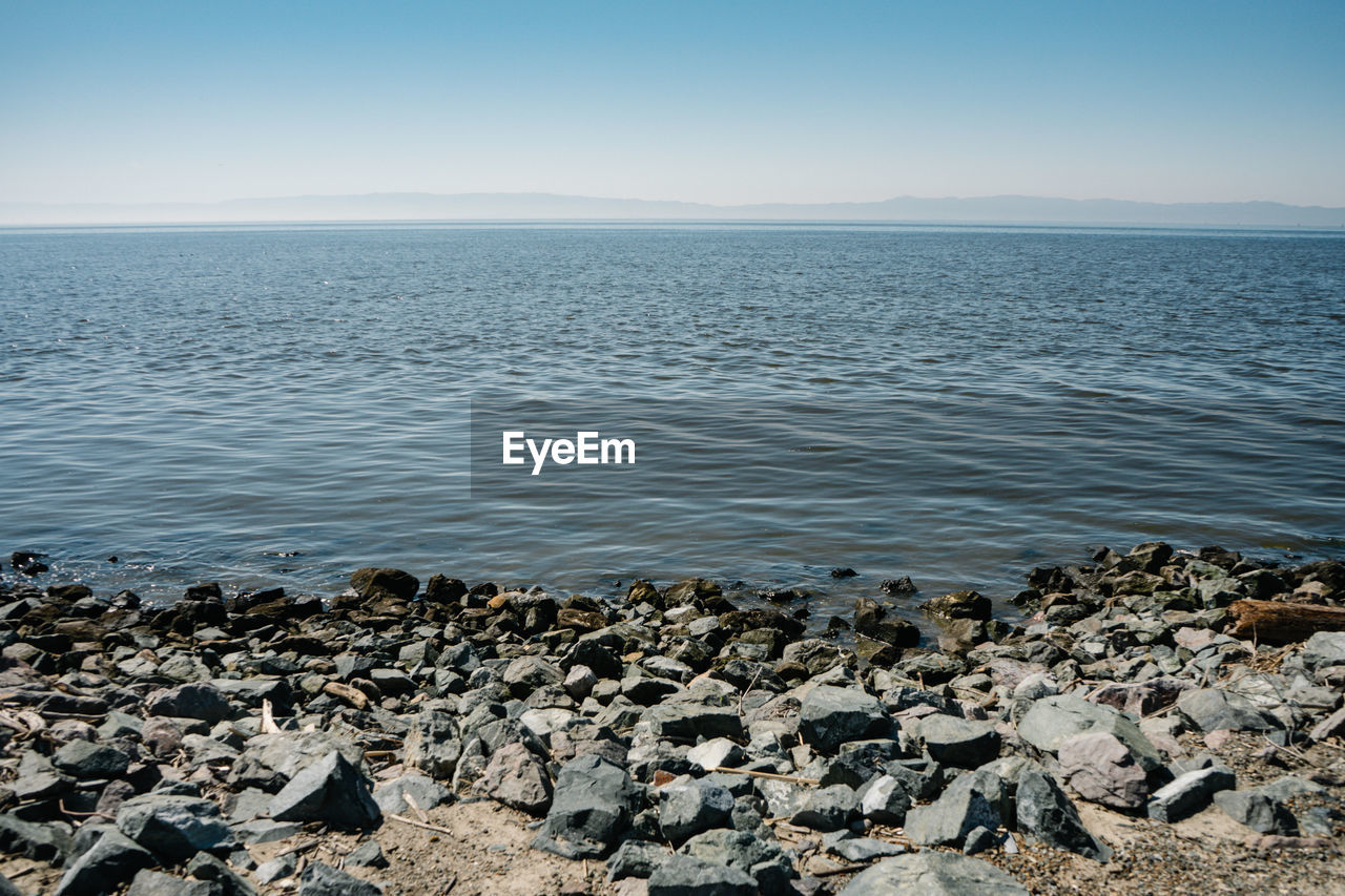 ROCKS ON BEACH AGAINST CLEAR SKY