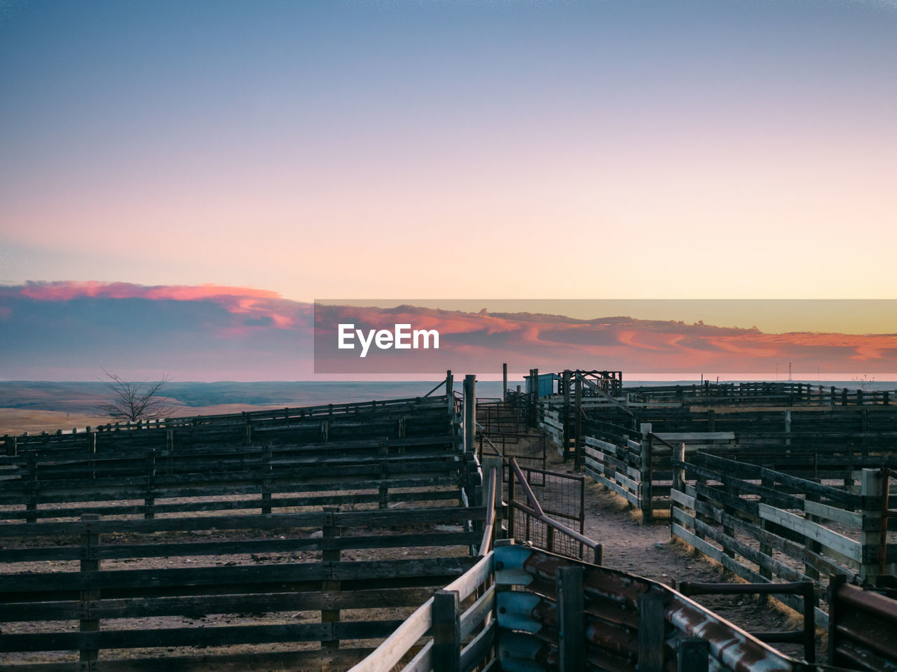 Empty animal pens against desert during sunset