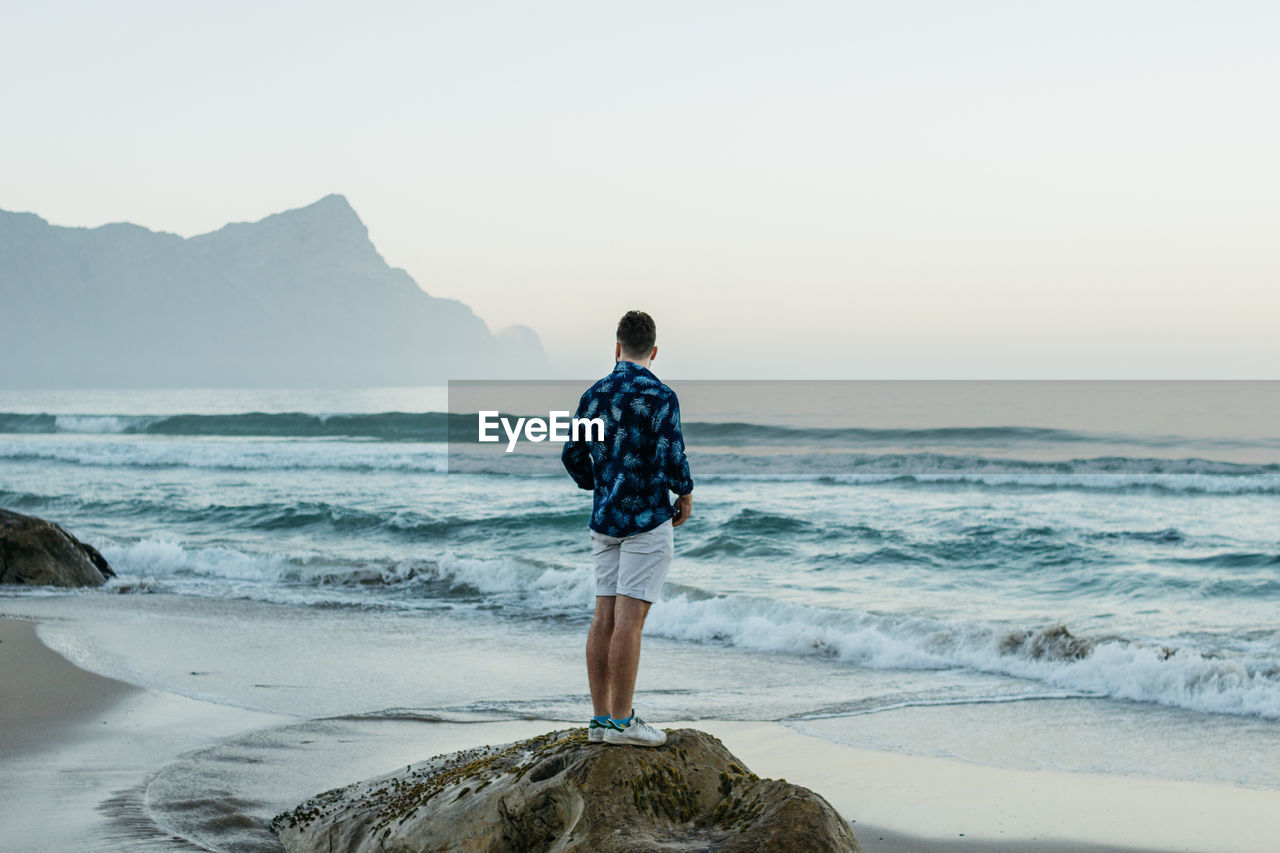 Man standing near the beach coastline.