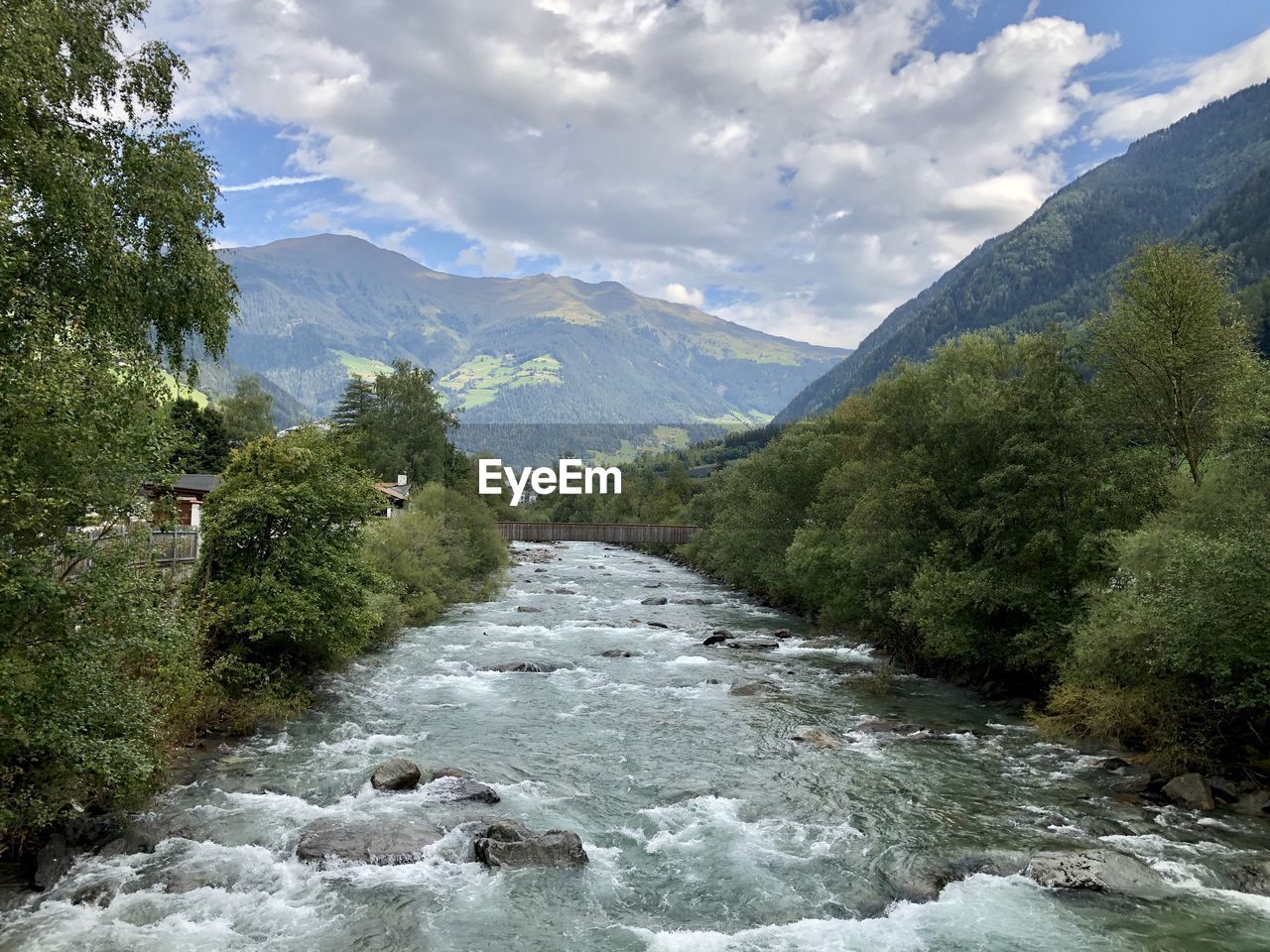 RIVER AMIDST GREEN MOUNTAINS AGAINST SKY