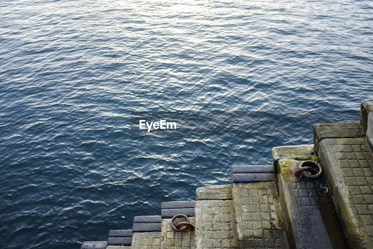 High angle view of steps by blue sea