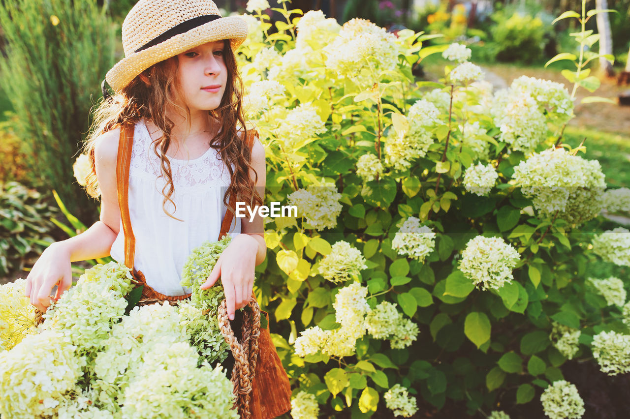 Girl standing amidst flowers in yard