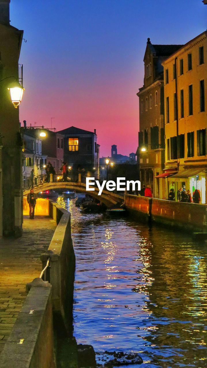 River amidst buildings against sky during sunset