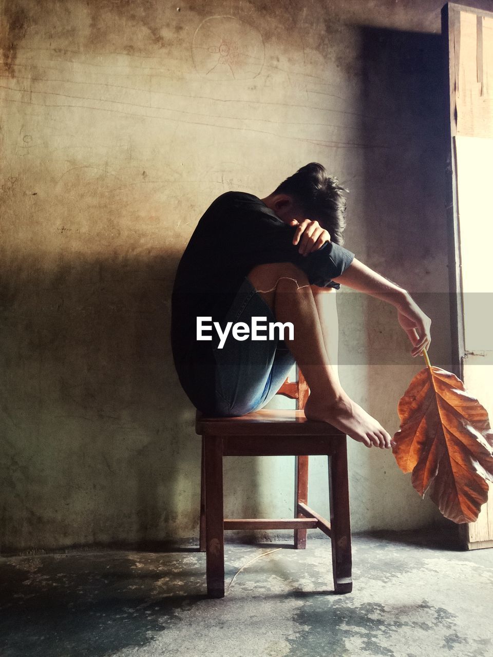 Man sitting on chair against wall