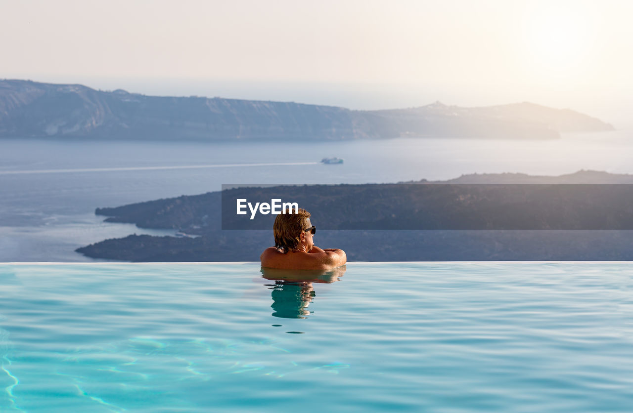 Rear view of shirtless man in infinity pool