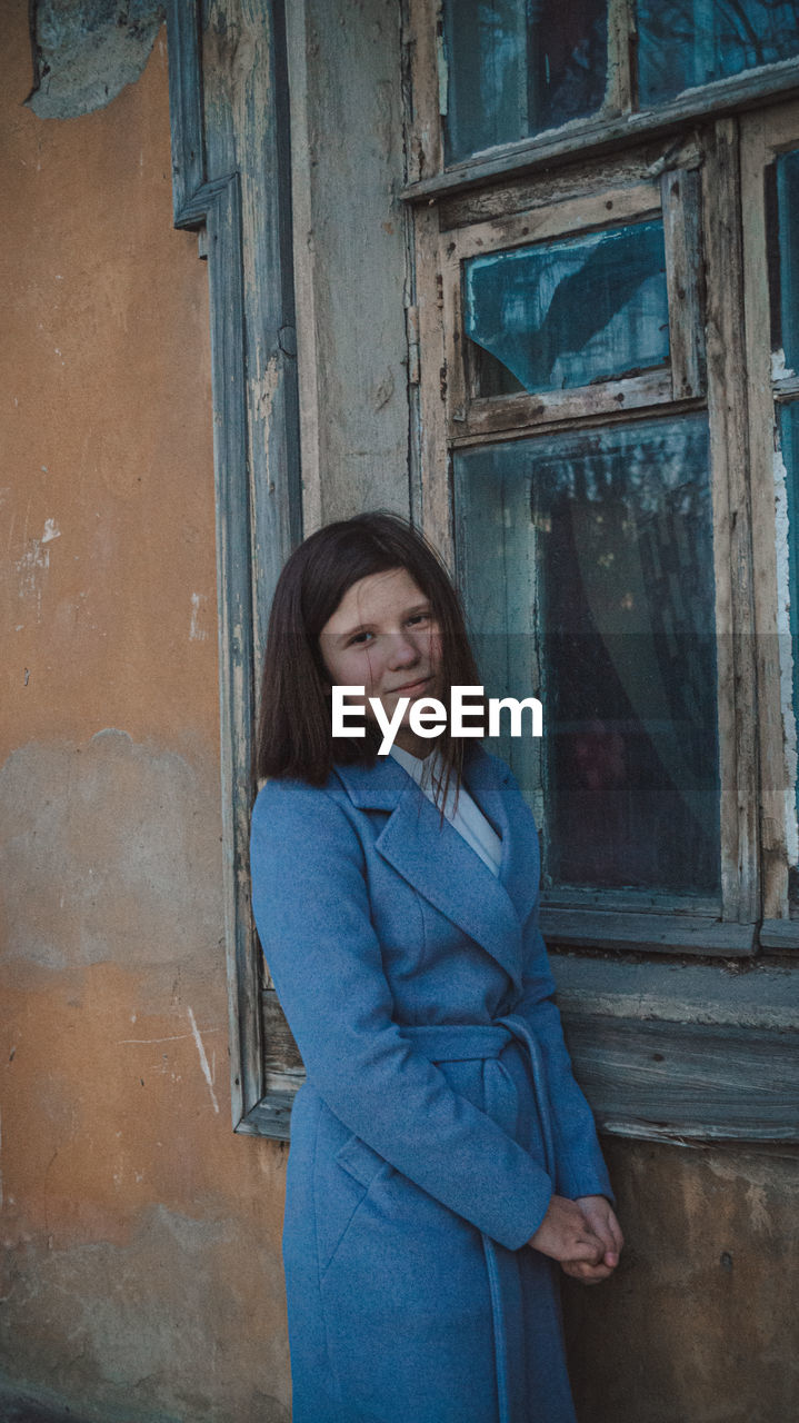 Portrait of woman standing against door