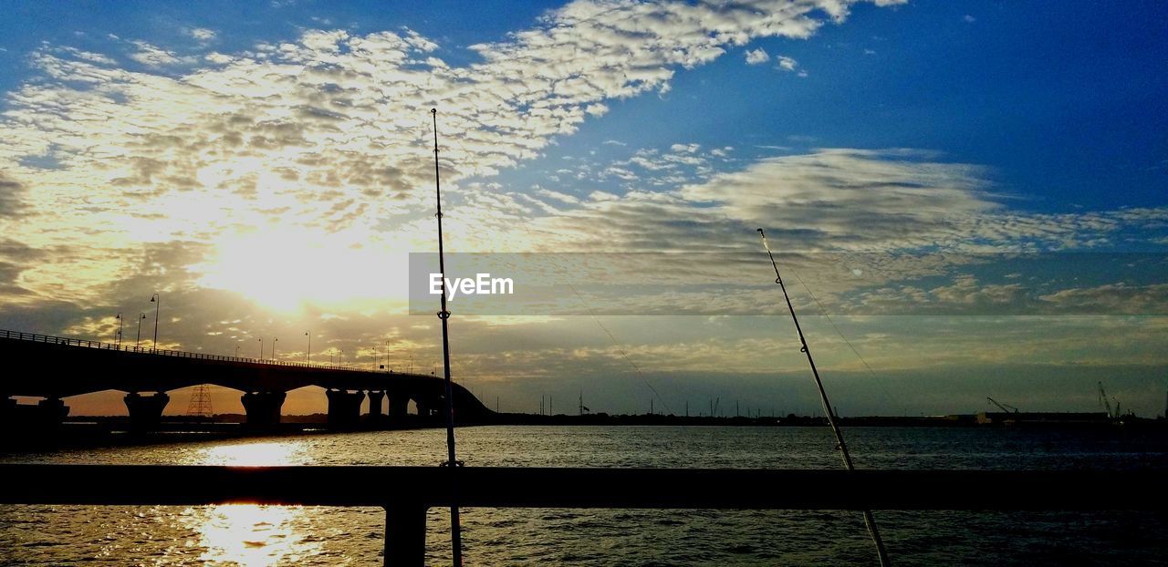 SILHOUETTE BRIDGE OVER SEA AGAINST SKY