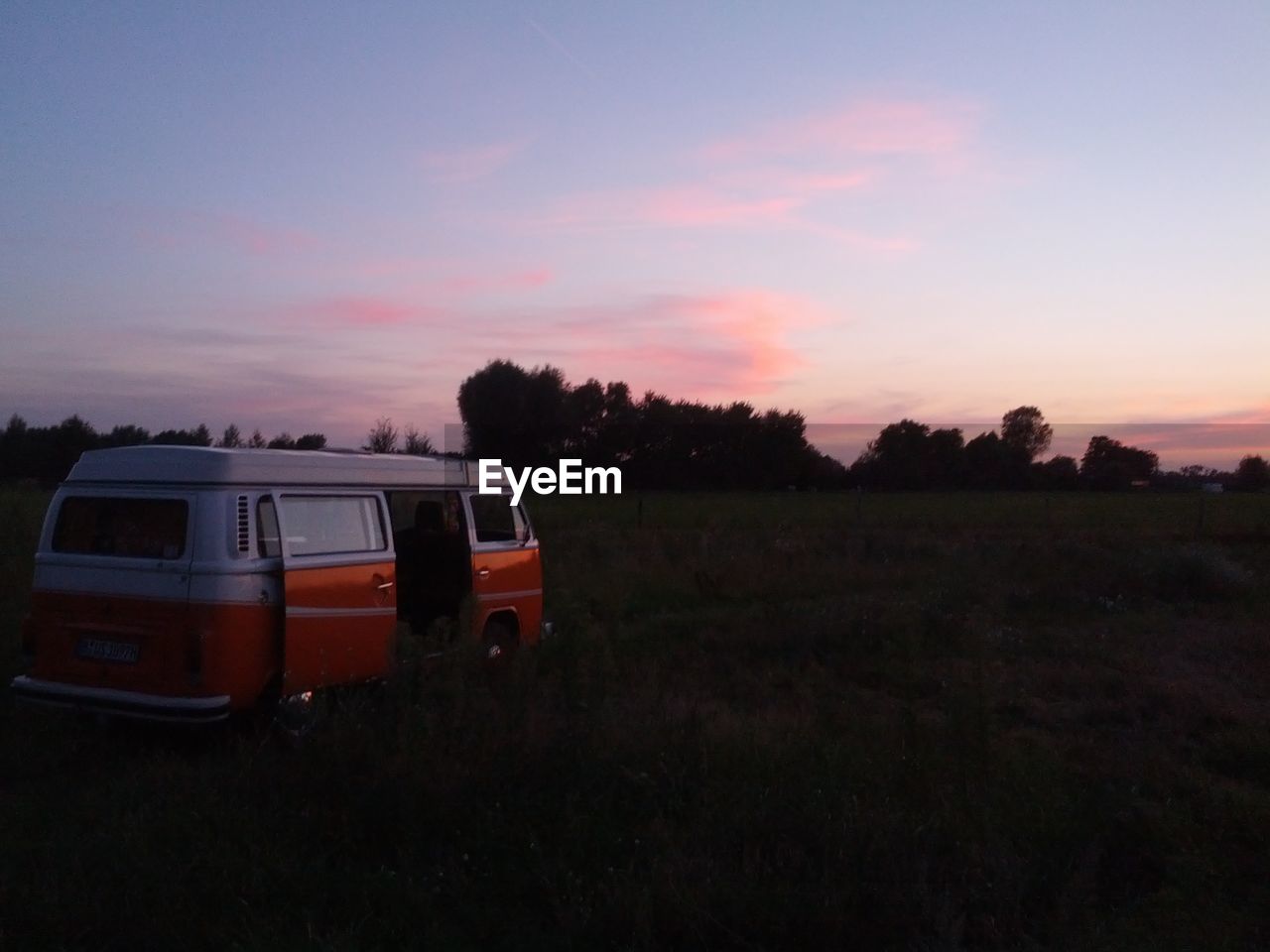 Van on grassy field at sunset