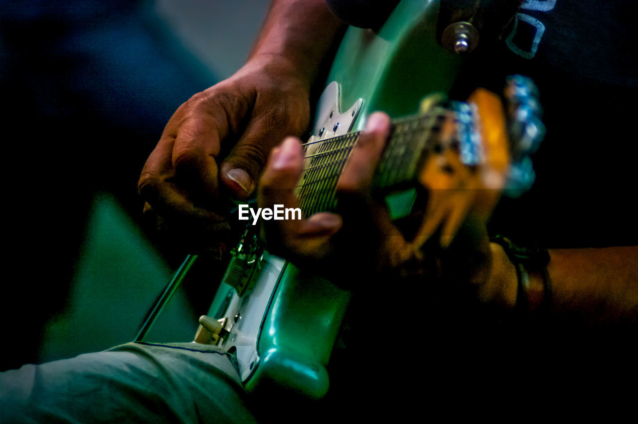 Midsection of man playing guitar