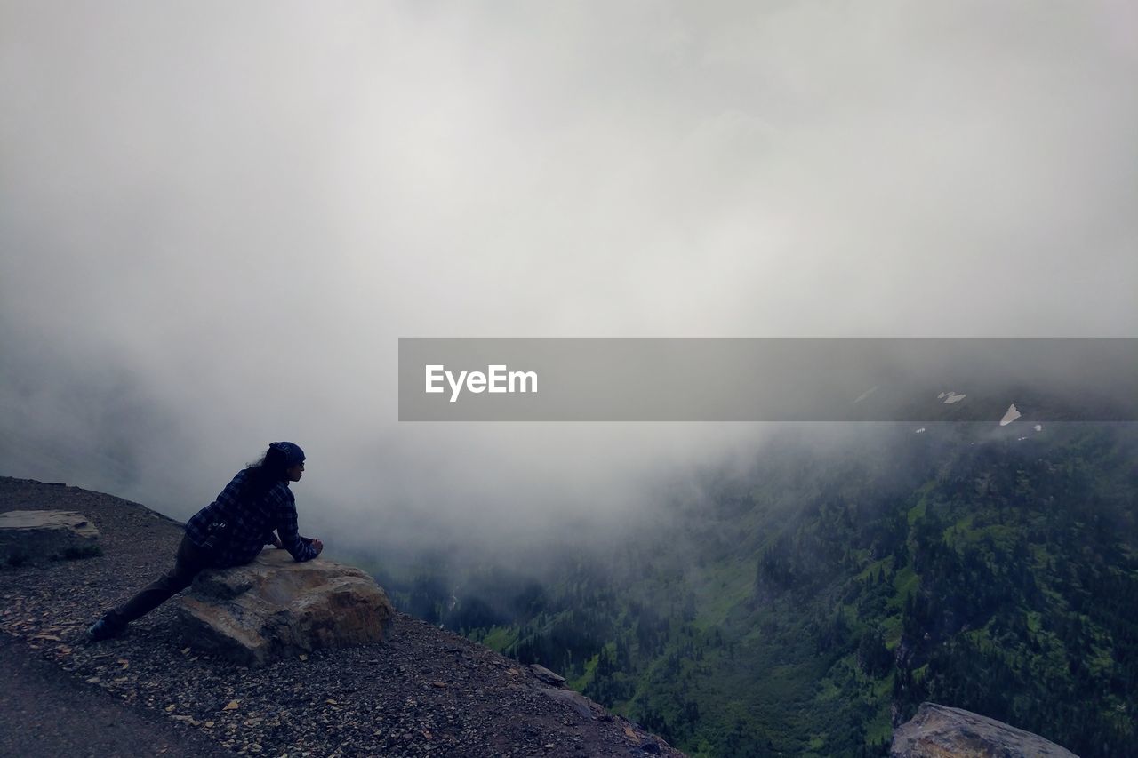 Female photographer looking at mountains and mist from a scenic vista in glacier national park.