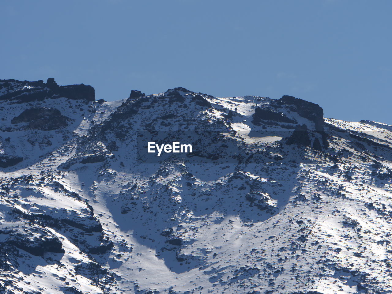 Aerial view of snowcapped mountains against clear blue sky