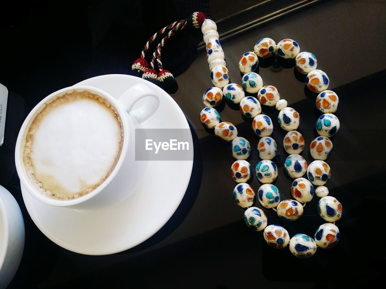 Close-up of necklace by coffee on table