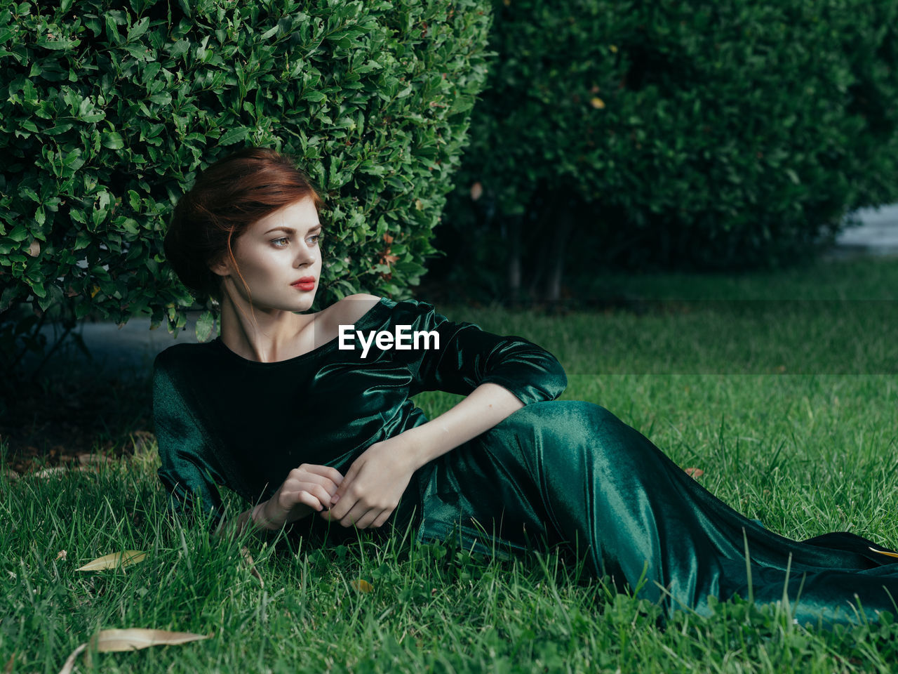 Young woman looking away while lying on grass