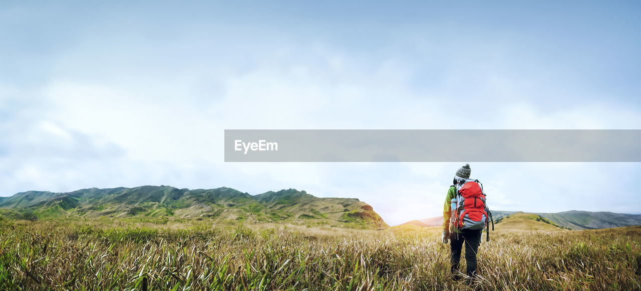 rear view of woman standing on mountain against sky