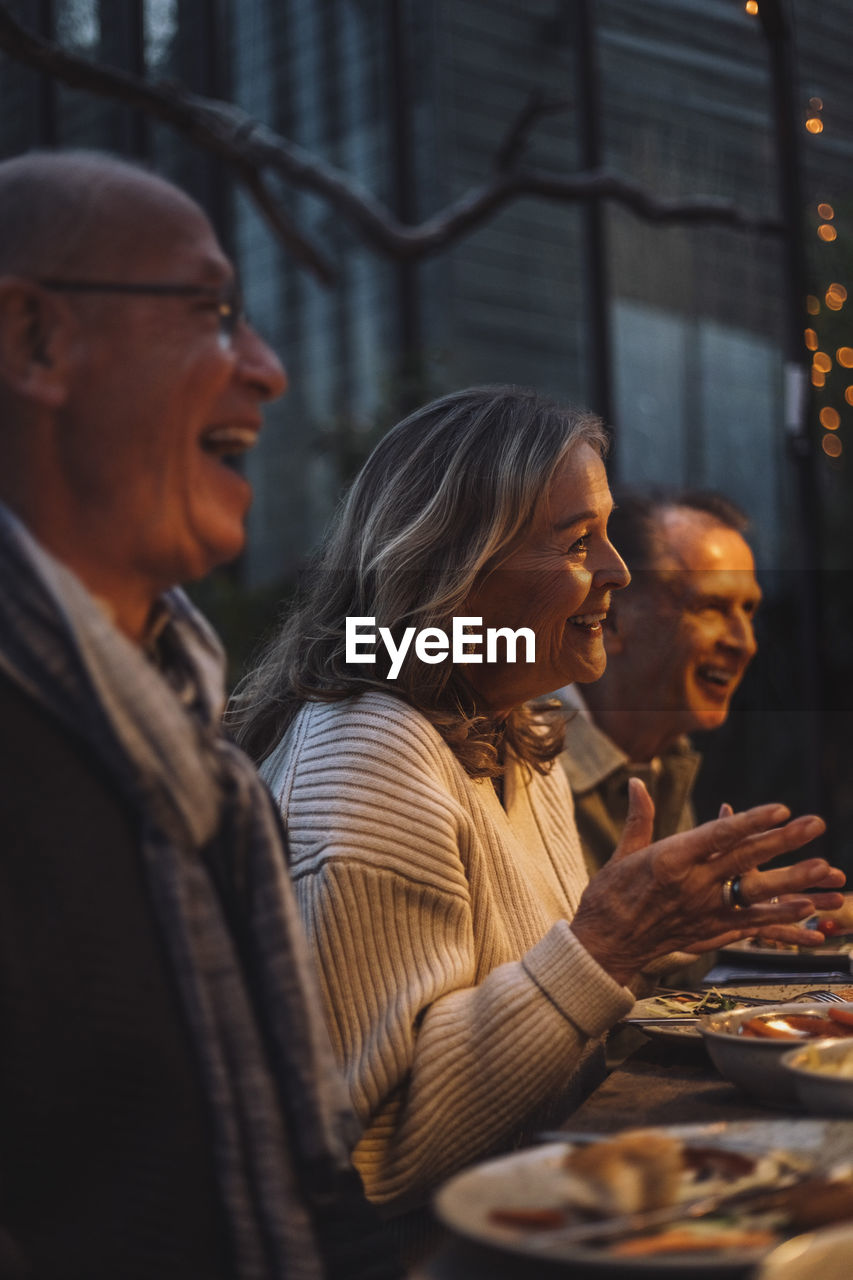 Happy senior woman gesturing while talking at dinner party