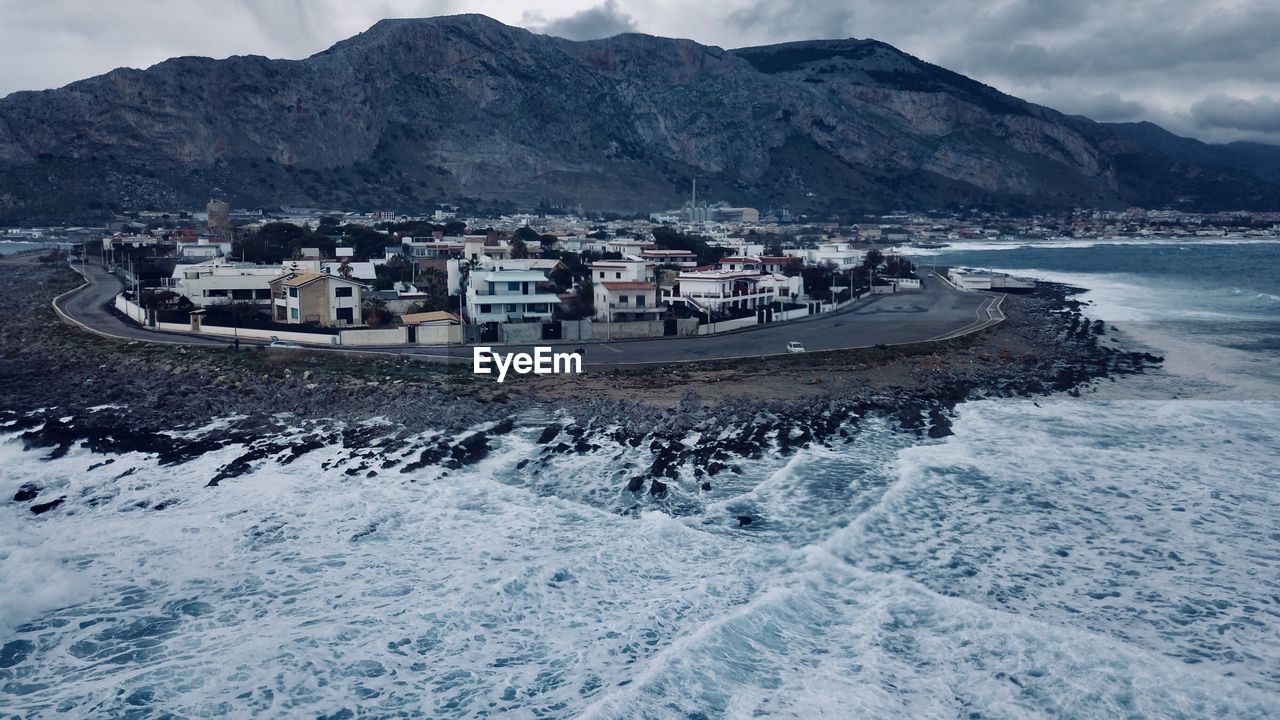 Scenic view of sea by mountains against sky