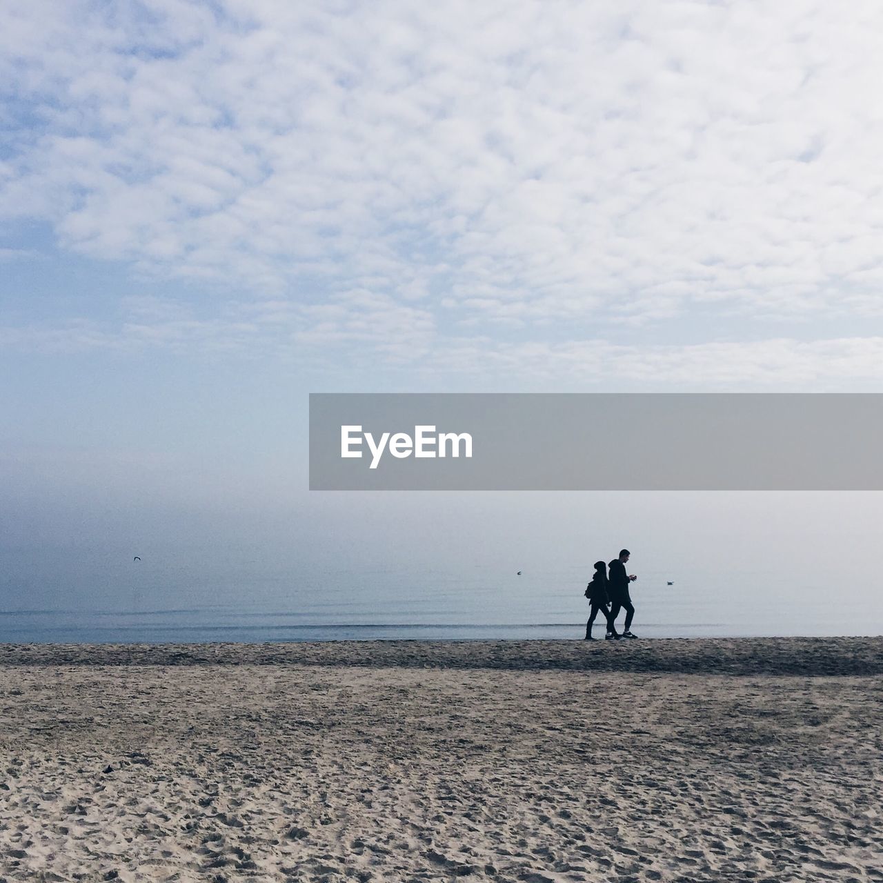 MEN WALKING ON SHORE AGAINST SKY