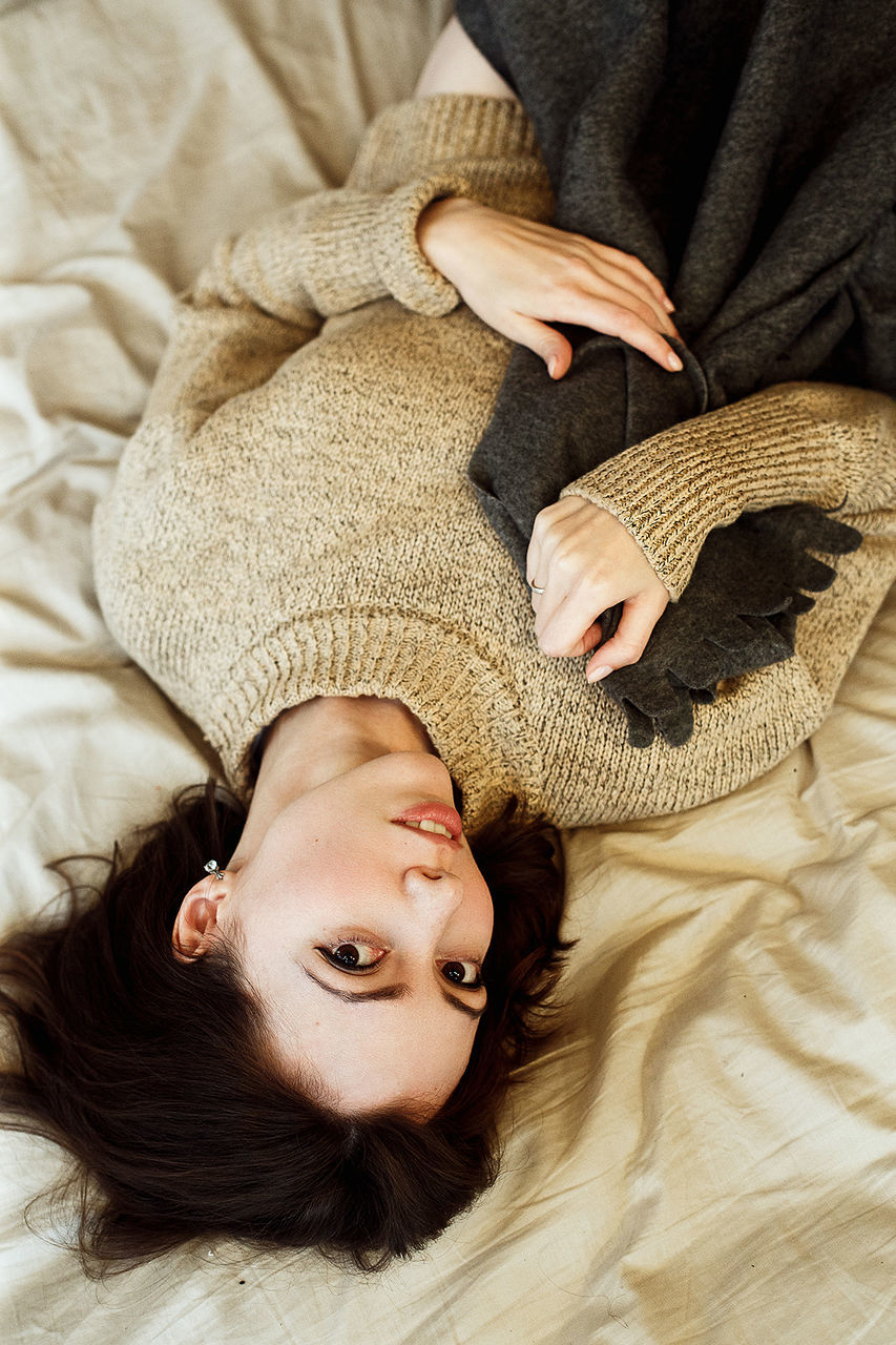 HIGH ANGLE PORTRAIT OF WOMAN LYING ON BED