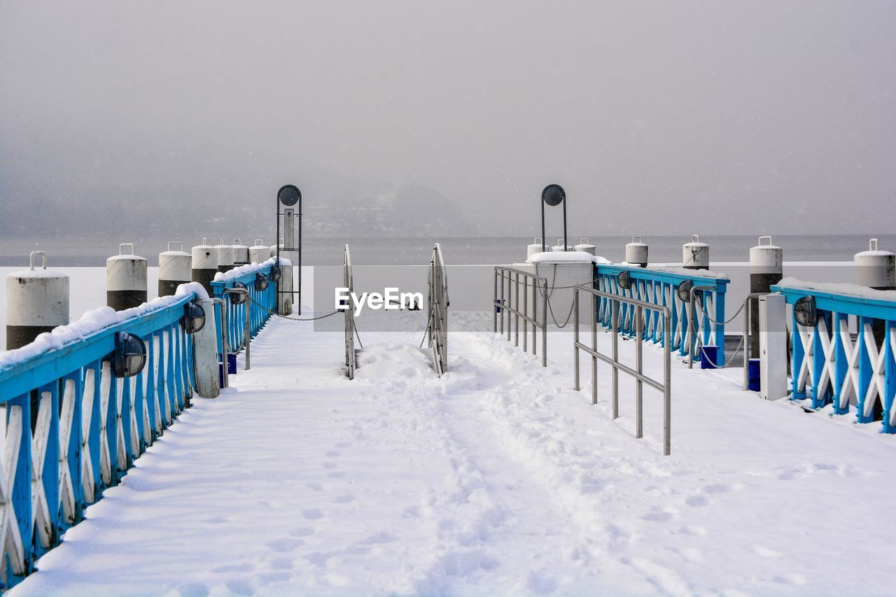 Snow covered field by railing during winter