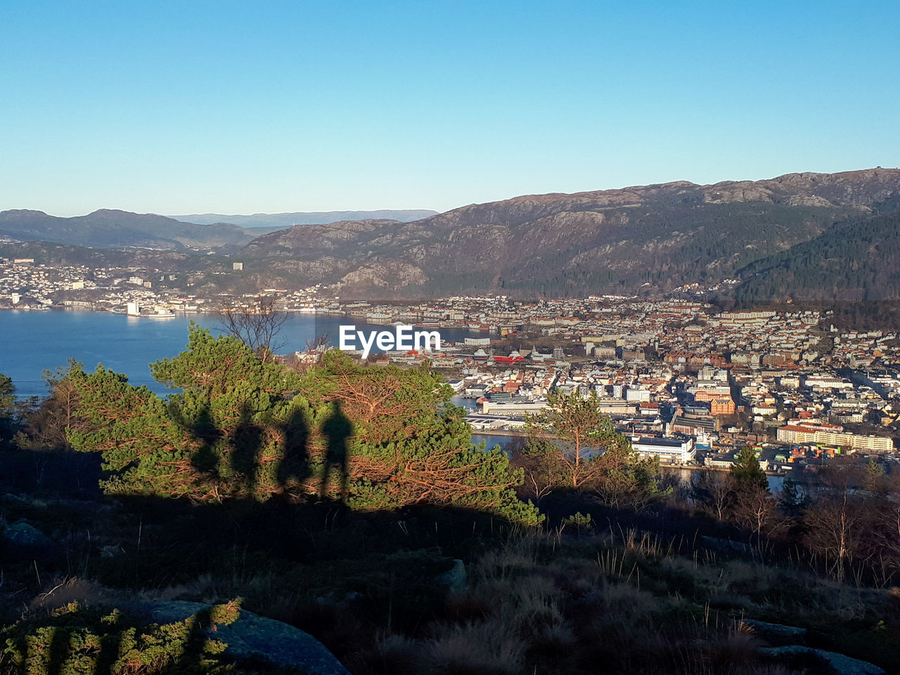 Aerial view of townscape and mountains against clear blue sky