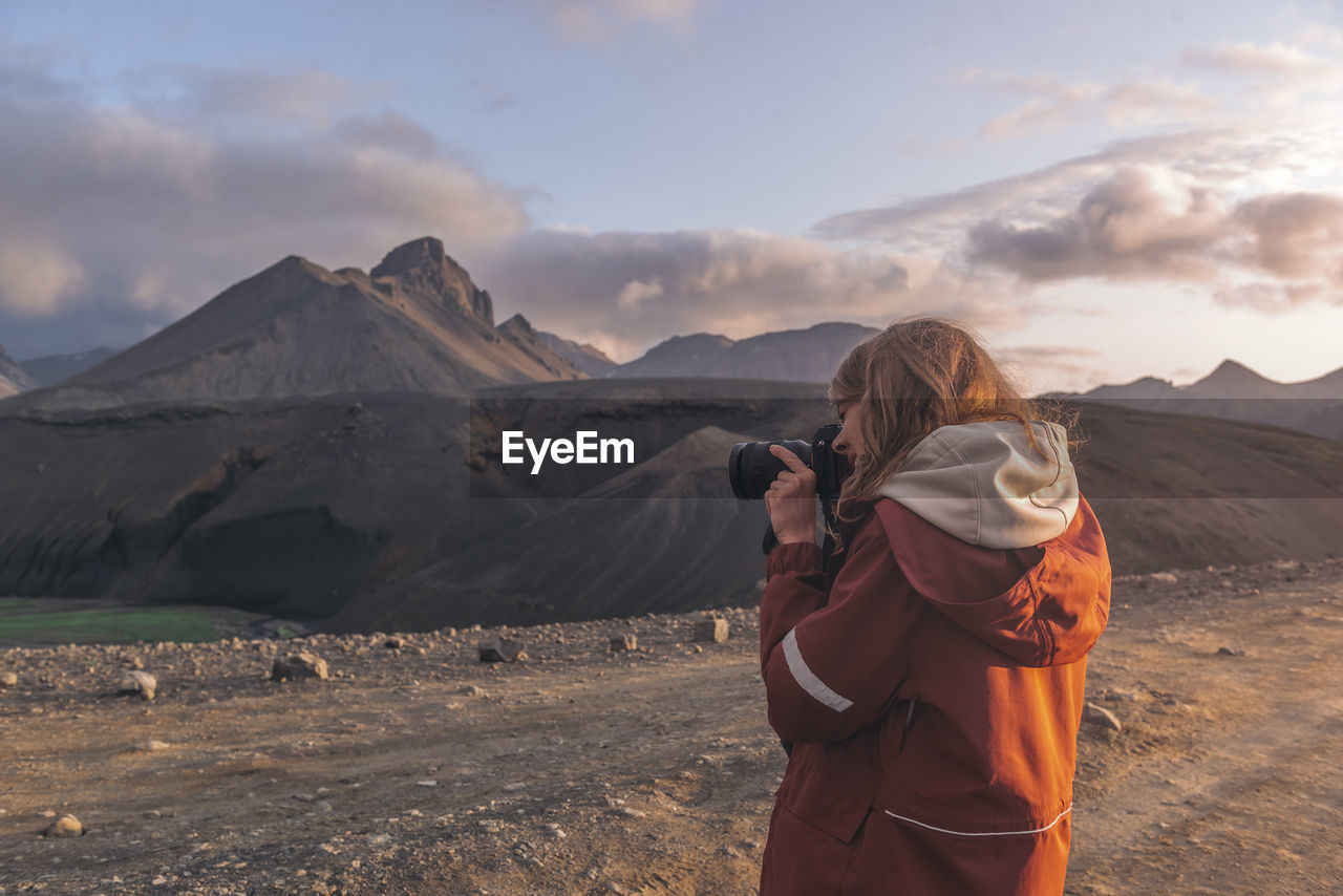 Young woman taking photographs of mountains in highlands of iceland