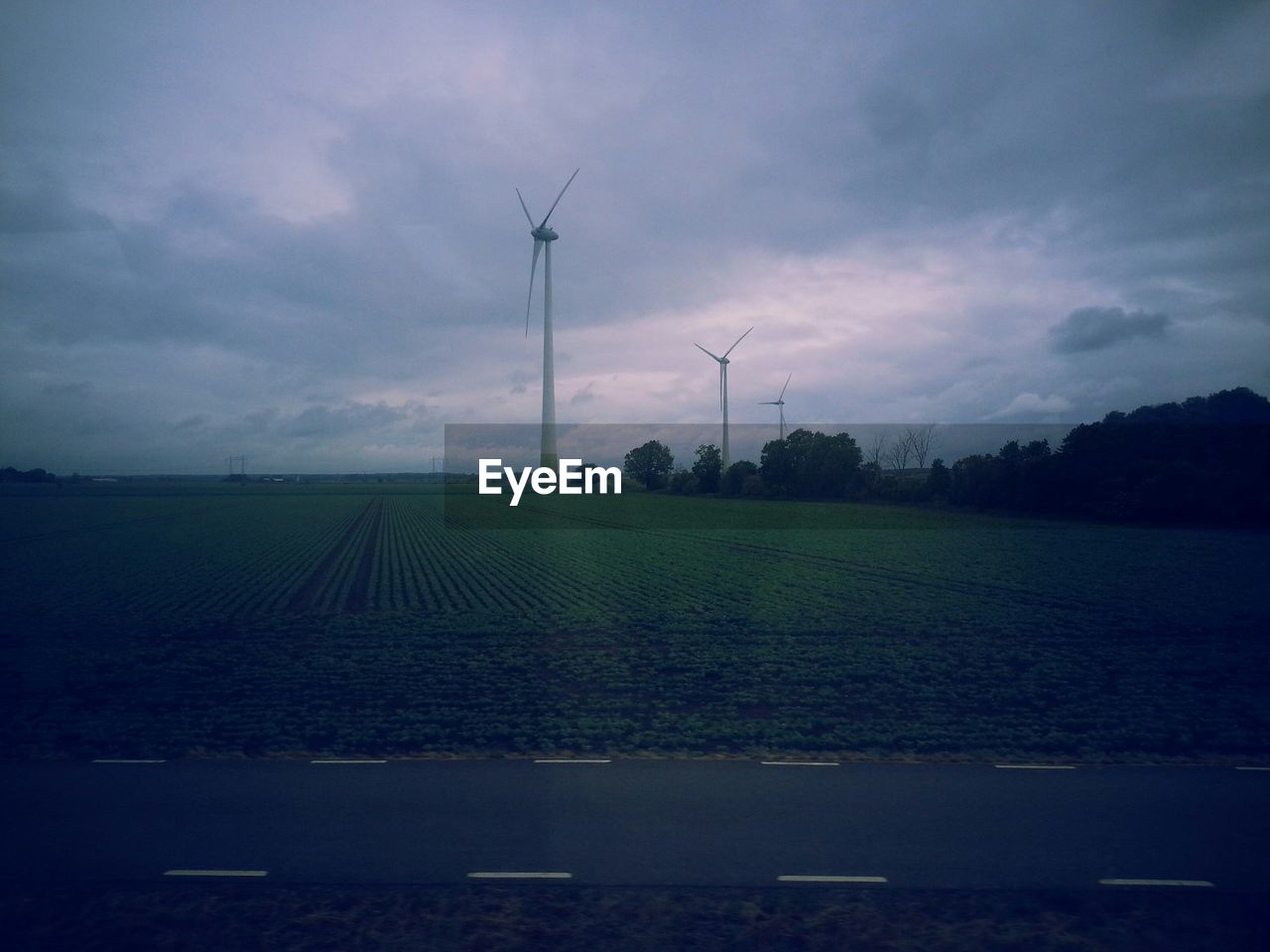 Wind turbines on field against sky